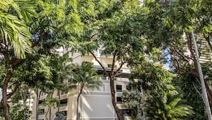 Un edificio alto con varios balcones, rodeado de abundante vegetación y árboles.