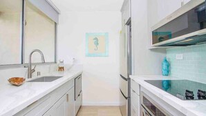 Une cuisine moderne avec des meubles blancs, un évier en acier inoxydable et un four encastré.