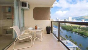 Un balcon avec une table et des chaises, donnant sur une rivière et offrant une vue sur la ville.