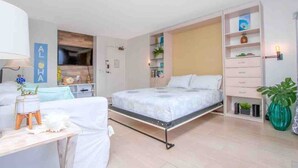 Une chambre moderne avec un lit, des tables de chevet, une armoire et un téléviseur.