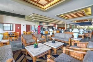 A spacious lobby with multiple seating areas, a coffee bar, and a Coca-Cola refrigerator.