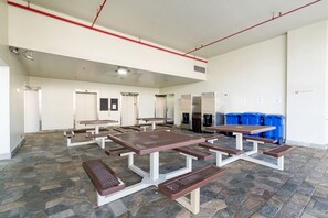 A spacious indoor area with multiple picnic tables and a stone-tiled floor. - Newly Renovated Pink Paradise Studio (Honolulu)