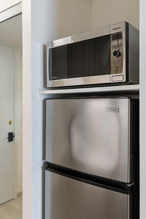 A compact kitchen with a stainless steel refrigerator and a microwave on top. - Newly Renovated Pink Paradise Studio (Honolulu)