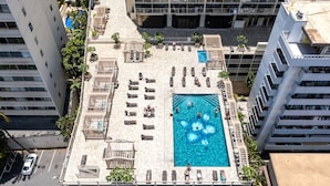 Ein Pool auf dem Dach mit Liegestühlen und einer brunnenartigen Wasserattraktion in Blütenform.