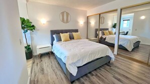 Une chambre moderne avec un grand lit, des tables de chevet, un miroir et une plante en pot.