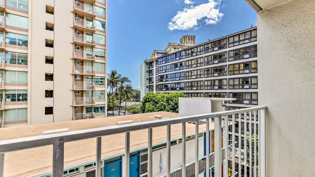A multi-story hotel with balconies, a clear sky, and palm trees in the background. - Island Style Studio Near the Shore! (Honolulu)