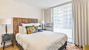 A hotel room with a large bed, two bedside tables, a TV, and a window with curtains. - Island Style Studio Near the Shore! (Honolulu)