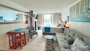 A hotel room with a bed, a sofa, a dining table, and a small table.