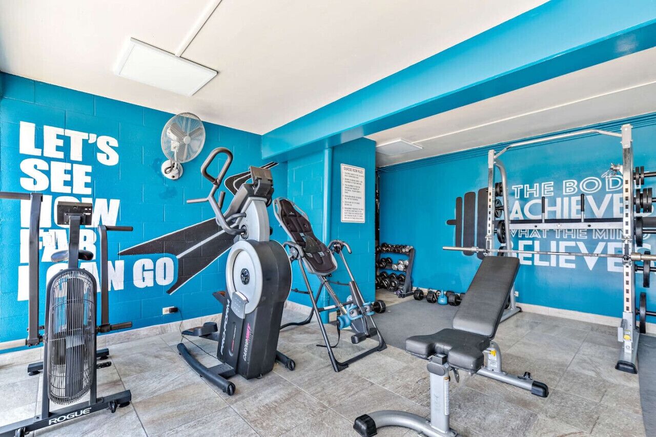 Une salle de sport aux murs bleus, équipée de matériel d’exercice et agrémentée de citations inspirantes.
