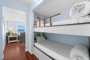 Une chambre avec un lit superposé donnant sur la mer, un canapé et une table de chevet avec une lampe.