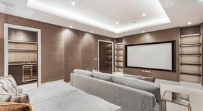 Een moderne woonkamer met een bank, een televisie en inbouwkasten.