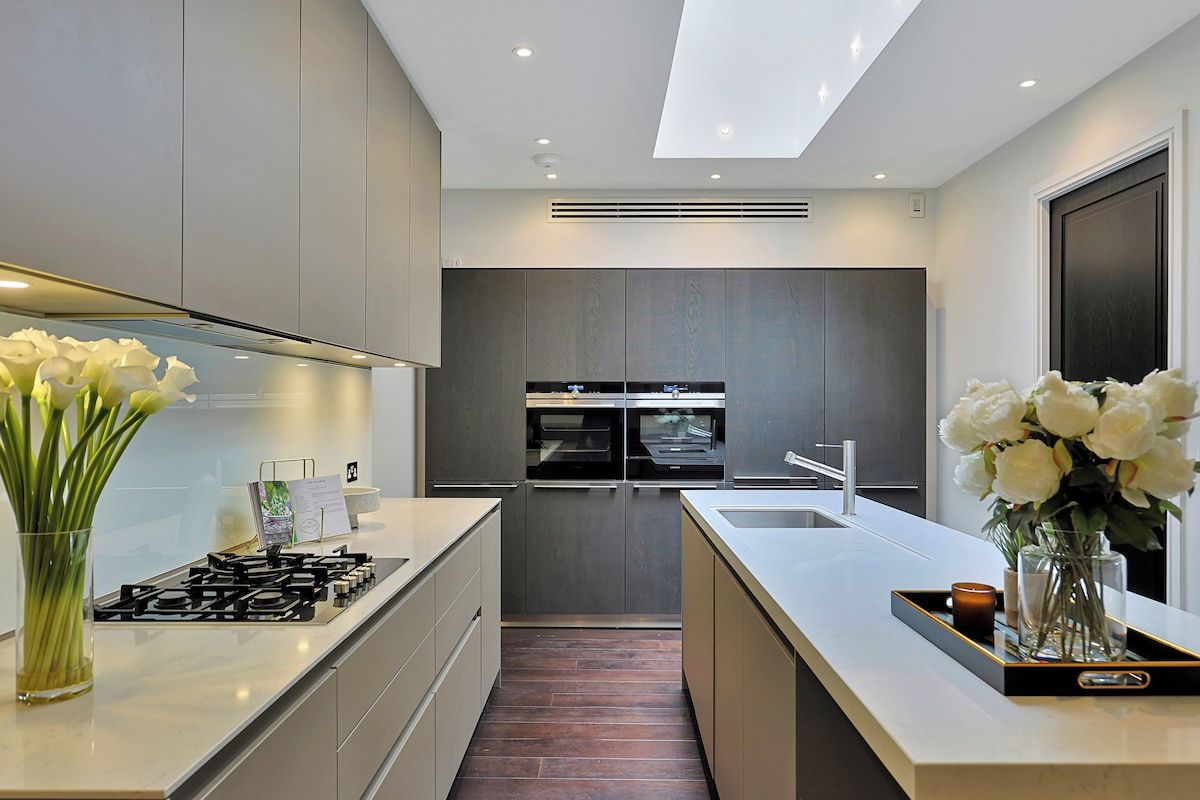 A modern kitchen with a central island, built-in appliances, and a skylight.