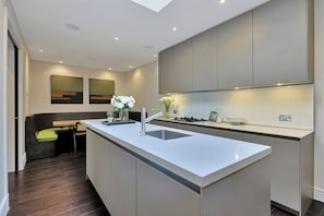 A modern kitchen with a central island, recessed lighting, and a built-in stove.