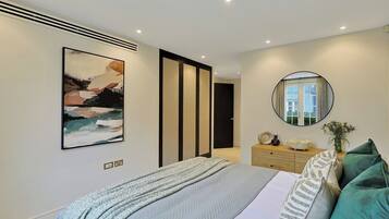 Une chambre à coucher moderne avec un lit, des œuvres d’art, un miroir et une commode.