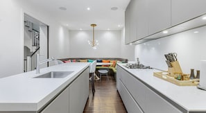 A modern kitchen with a central island, a built-in stove, and a dining area with a sofa and chairs.