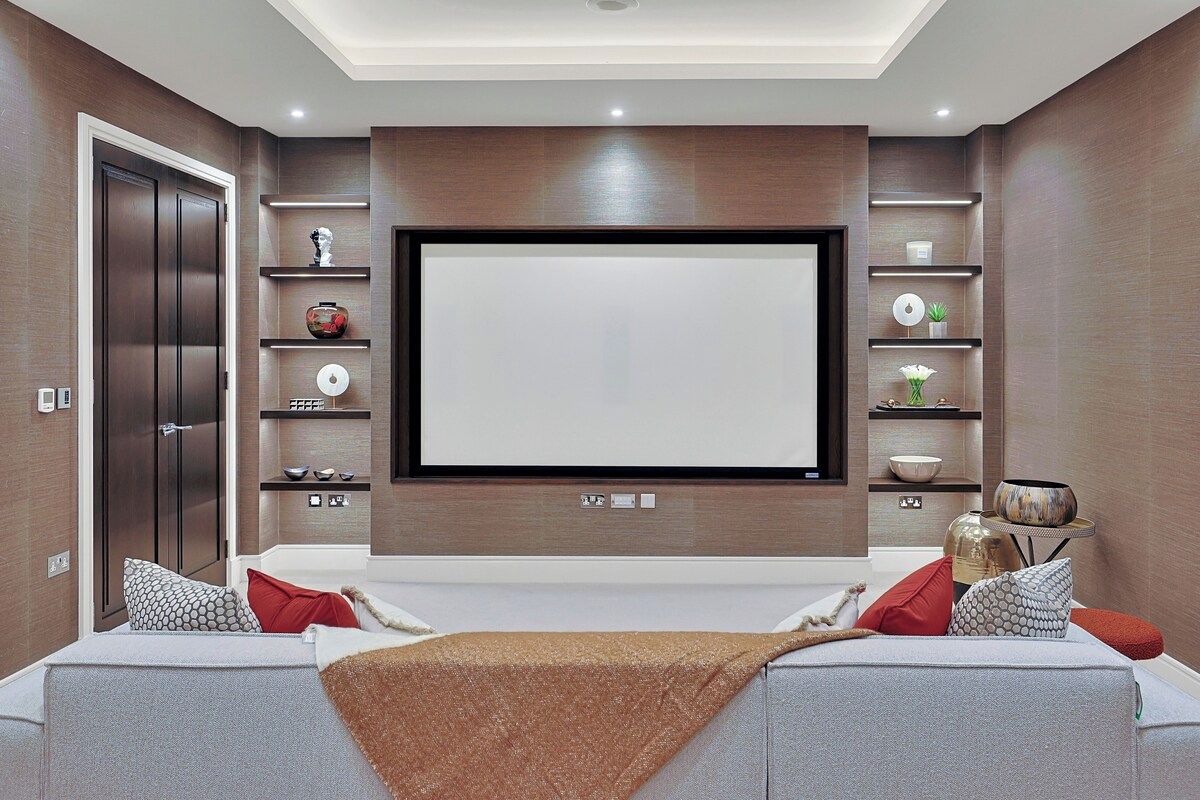 A modern living room with a flat-screen TV, built-in shelves, a sofa, and a door.
