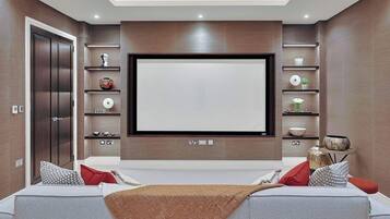 A modern living room with a flat-screen TV, built-in shelves, a sofa, and a door.