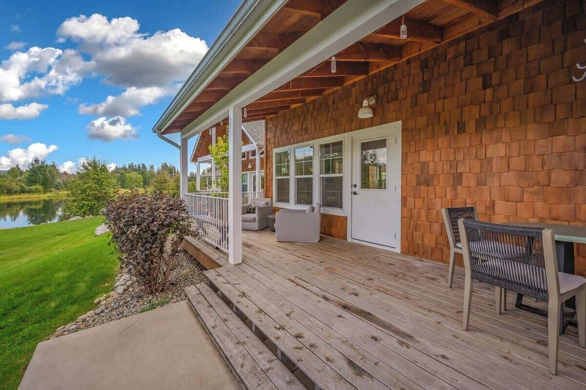 A covered deck with outdoor furniture, a view of a lake, and a brick wall.