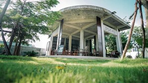 A stone age-themed pavilion with a curved roof, surrounded by greenery and trees. - Stone Age Boutique  (Kampot)