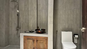 A bathroom with a shower, toilet, and wooden cabinet. - Stone Age Boutique  (Kampot)