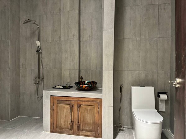 A bathroom with a shower, toilet, and wooden cabinet. - Stone Age Boutique  (Kampot)