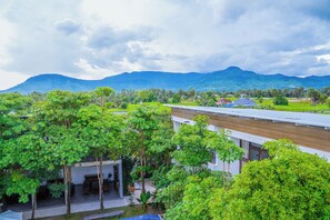 A modern building with a flat roof, surrounded by lush greenery and a mountainous backdrop. - Stone Age Boutique  (Kampot)