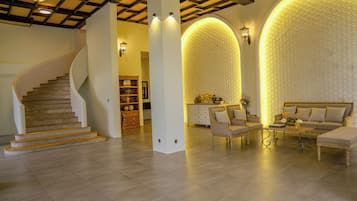 A spacious living area with a curved staircase, a sofa set, and a decorative wall with a scalloped pattern.