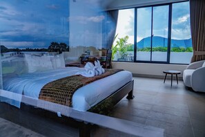 A bedroom with a large bed, a view of the outdoors through a window, and a small table. - Stone Age Boutique  (Kampot)