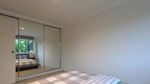 A bedroom with a bed, a large mirror, and a sliding door closet. - Gorgeous Griffith 2Bed/1Bath Pad (Griffith)
