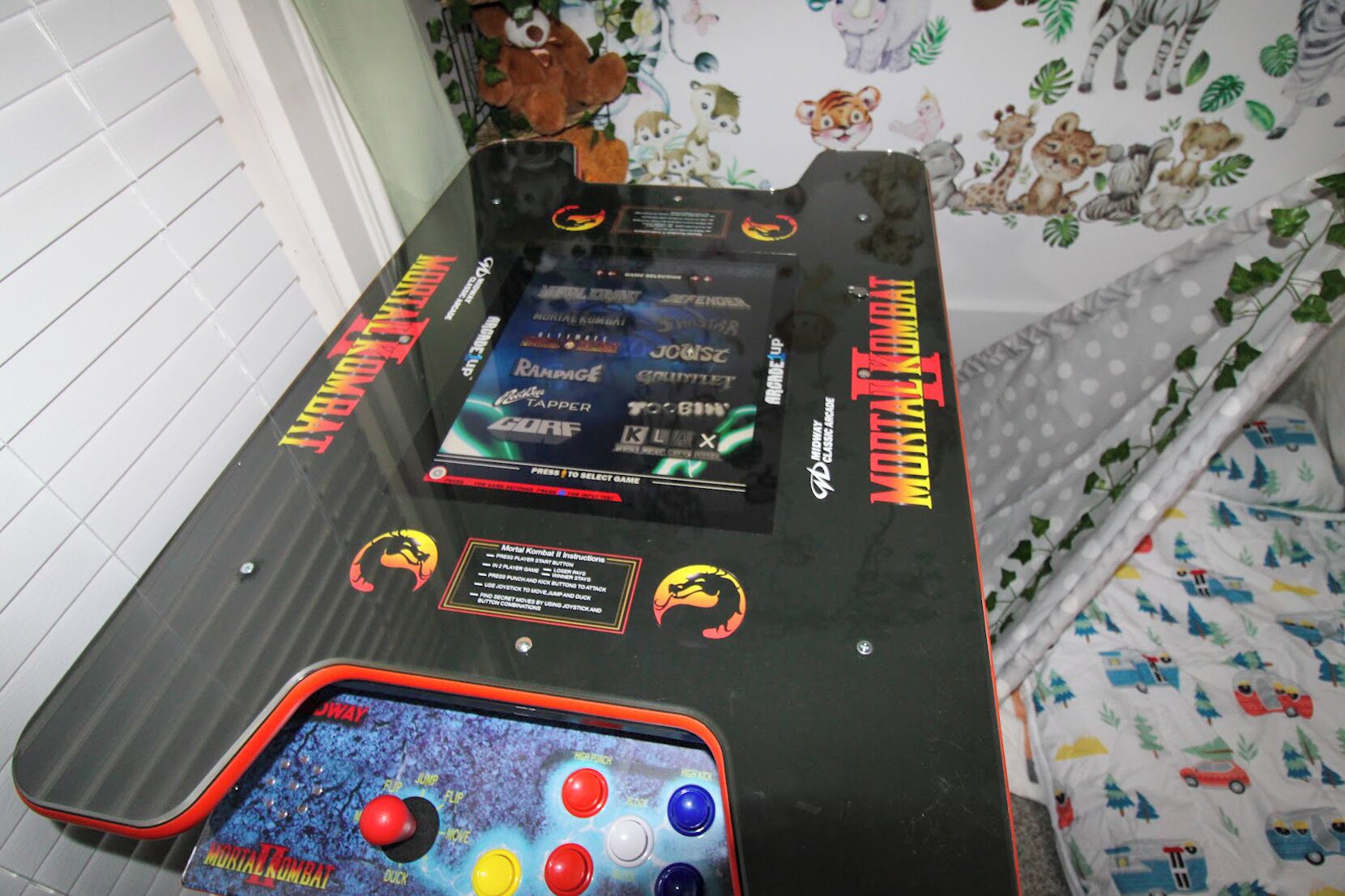 Mesa de fliperama com instruções do jogo Mortal Kombat II e um joystick.