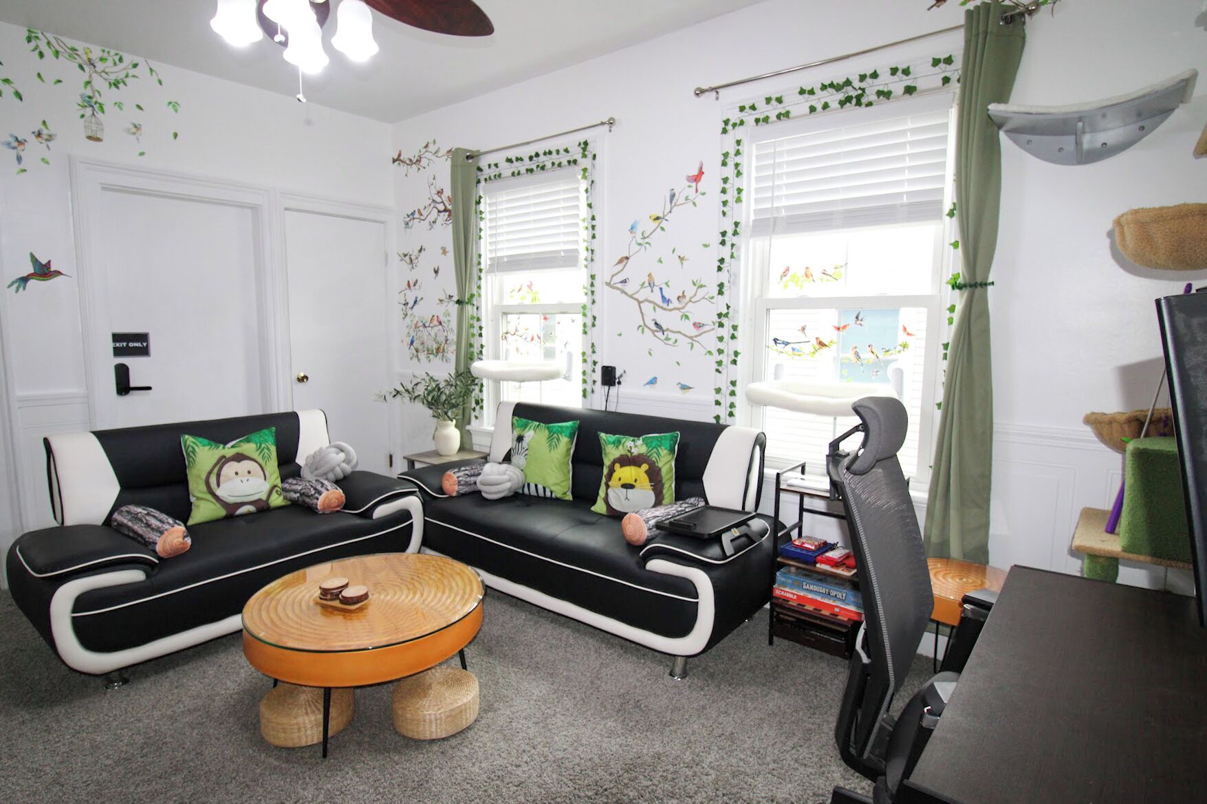 A living room with a black and white sofa set, a round wooden coffee table, and a cat tree.