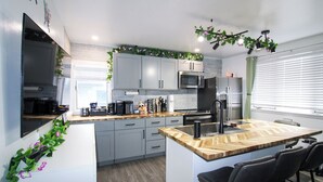 Una cocina moderna con armarios grises, una isla de madera, taburetes de bar y un microondas empotrado.