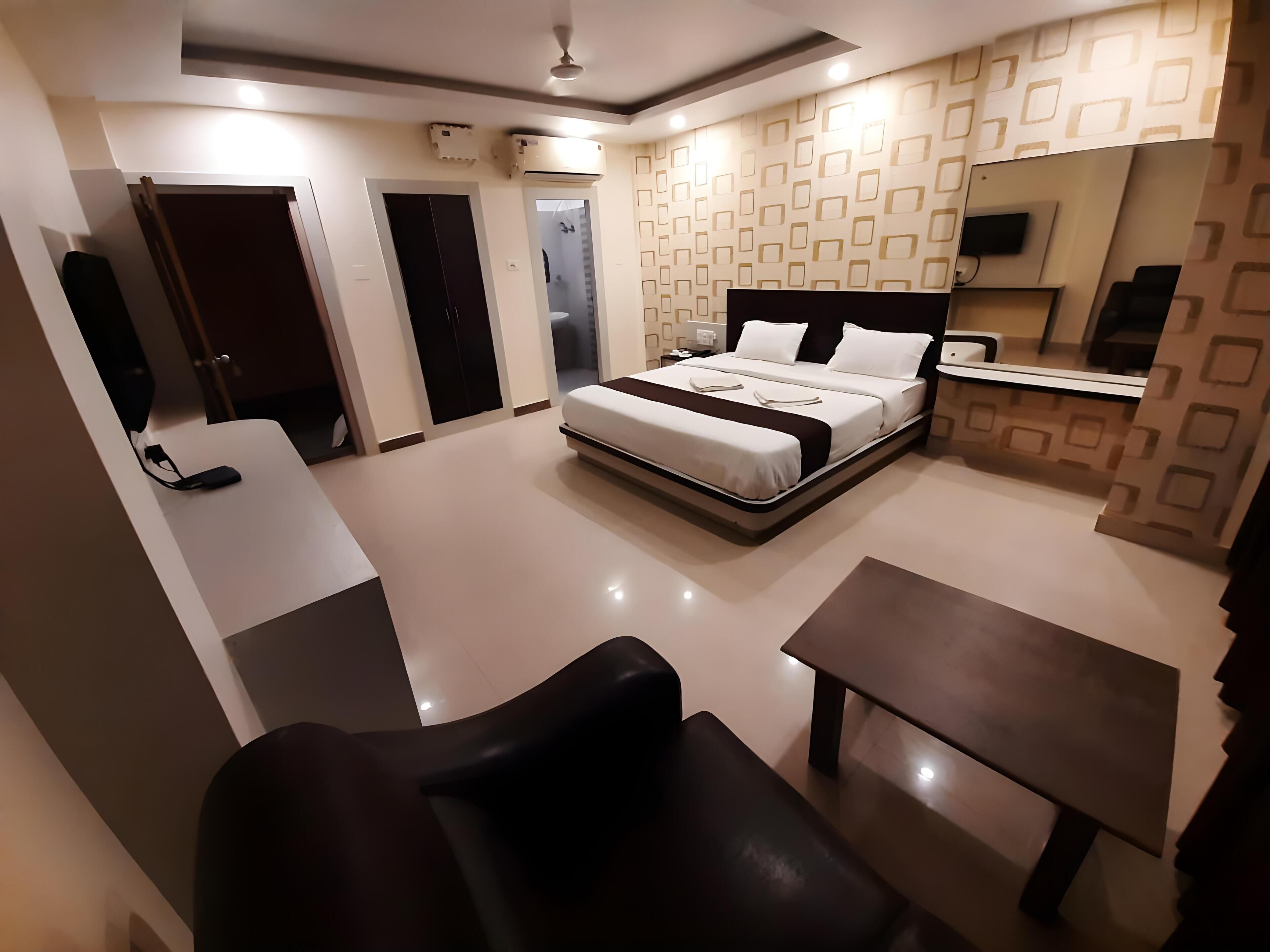 A modern hotel room with a bed, a desk, a chair, and a small table.