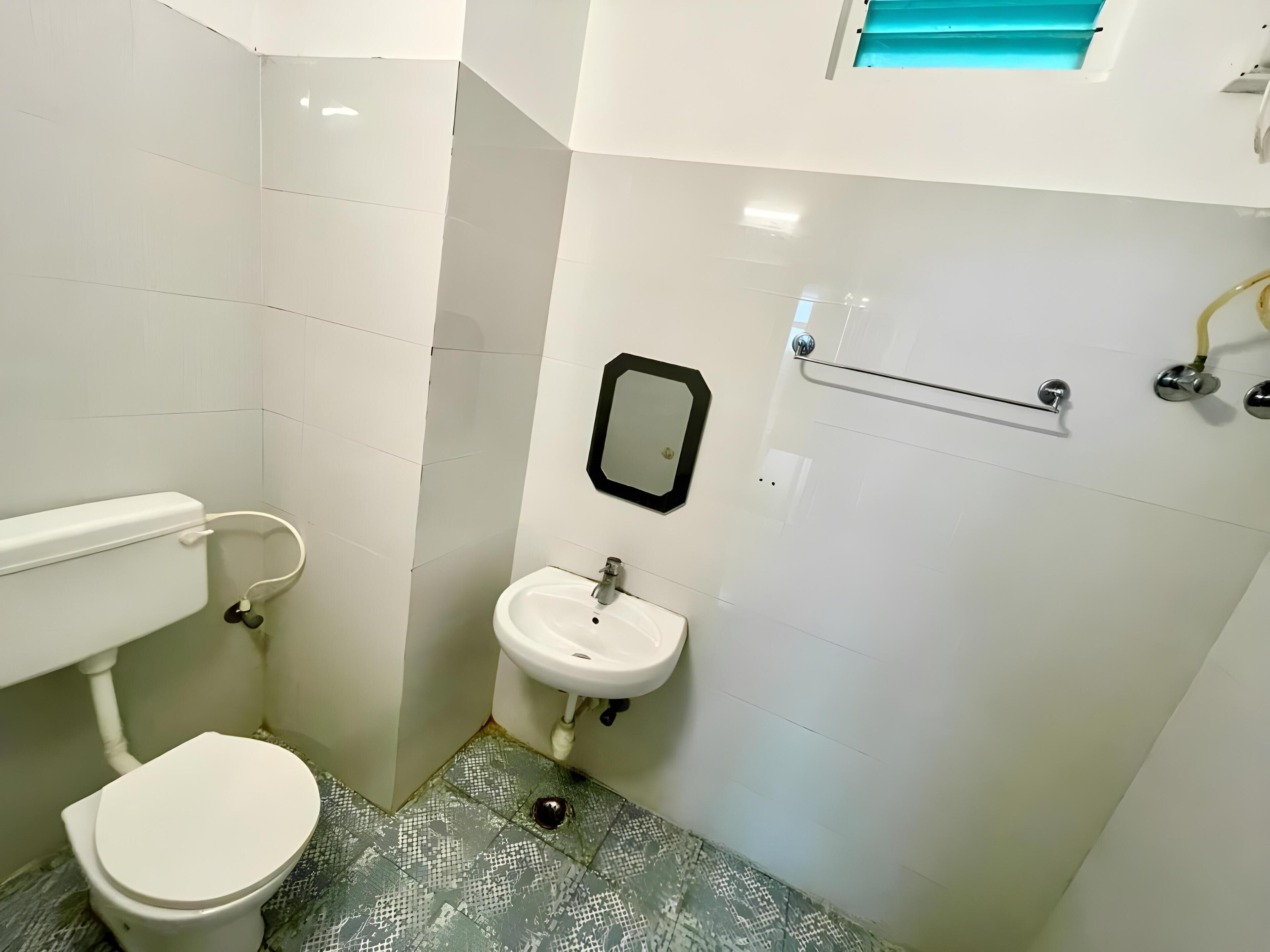 A small bathroom with a toilet, sink, and mirror.