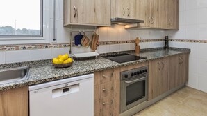 A modern kitchen with wooden cabinets, a built-in oven, and a granite countertop. - Llevant by Interhome (Creixell)
