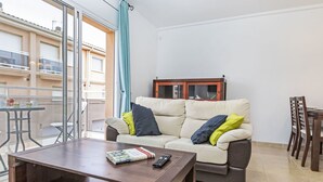 A living room with a sofa, a coffee table, a cabinet, and a dining area with chairs. - Llevant by Interhome (Creixell)
