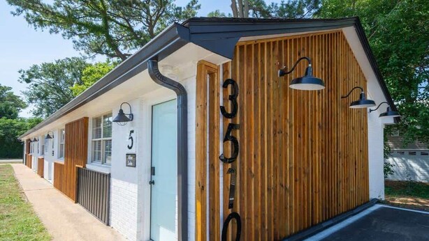 A row of modern, single-story cabins with a wooden facade and black-framed windows. - OV Mosaic - Coconut Suite (Norfolk)