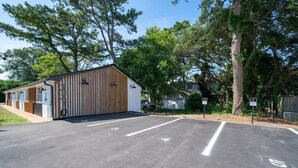 Un pàrquing amb un edifici que té un teulat inclinat i panells de fusta verticals.