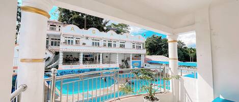 A hotel with a pool area, a staircase, and a balcony with a potted plant.
