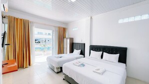 A hotel room with two beds, a large window with curtains, a minibar, and a view of a pool. - Agave Hotel By Helocus (Pematang Pane)