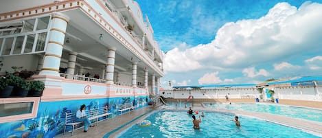 A swimming pool area with a large building featuring multiple balconies and a mural of sea life.