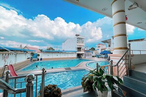 A swimming pool area with a view of a building with a balcony and a sign that reads "ACADEMY". - Agave Hotel By Helocus (Pematang Pane)