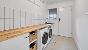 Un lavadero pequeño con mostrador de madera, lavadora y secadora.