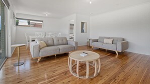 Una sala de estar moderna con dos sofás grises, una mesa de centro redonda y suelo de madera.