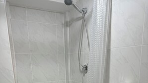 Une salle de bain avec douche, toilettes et lavabo.