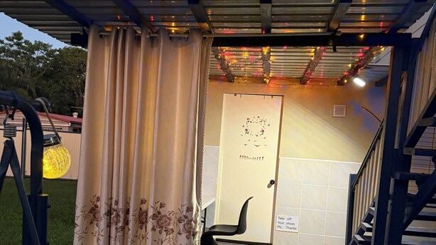 Un espace extérieur abrité, doté d’une porte, d’une chaise et d’un panneau.