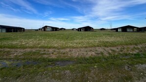 A series of modern, dark-colored buildings in a grassy field under a clear sky. - Holiday Home in Wissenkerke With Garden (Wissenkerke)
