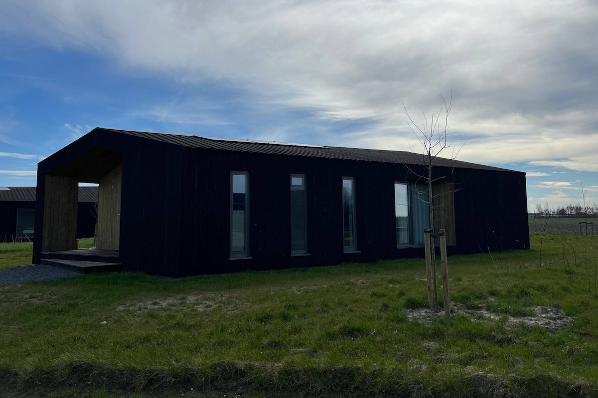 A modern, dark-colored building with a flat roof and large windows.
