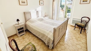Een slaapkamer met een bed, nachtkastjes, een stoel en een raam met uitzicht.
