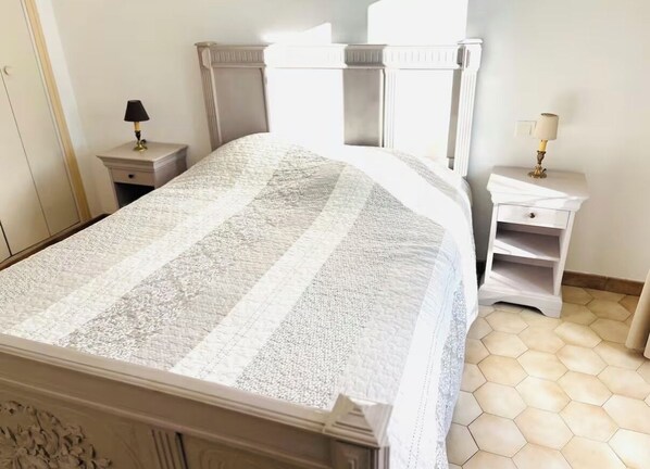 A neatly arranged bedroom with a large bed, a nightstand, and a bedside table.